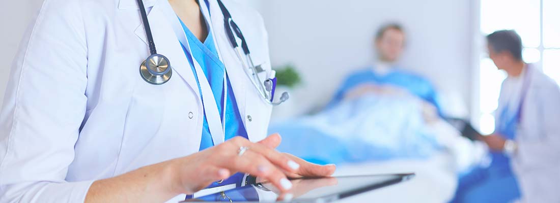 ;женщина врач с планшетом в руках на фоне больничной палаты с пациентом